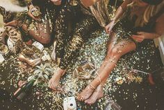 three women sitting on the floor with confetti all over them and one is holding a camera