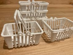 four white plastic baskets sitting on top of a wooden table next to each other with handles