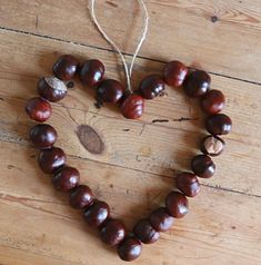 a heart made out of acorns sitting on top of a wooden floor next to a string