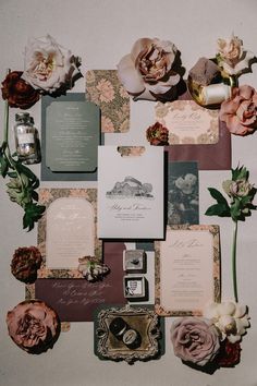 an assortment of wedding stationery with flowers and cards on the wall in front of them