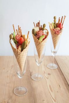 three glasses filled with different types of food on top of a wooden table next to each other