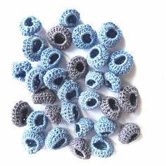 crocheted blue and gray beads with holes in the middle on a white surface