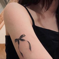 a woman's arm with a tattoo on it that has a black ribbon and a bow