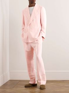 a man in a pink suit standing on the floor with his hands in his pockets