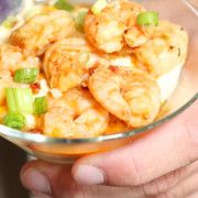 a person holding a glass bowl filled with shrimp and celery