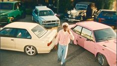 a man standing in the middle of a parking lot next to parked cars