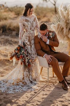 a bride and groom sitting on chairs in the desert