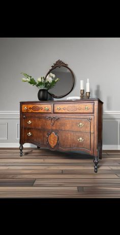 an antique dresser with mirror and vase on top