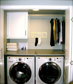 a washer and dryer in a small room with clothes hanging on the rack