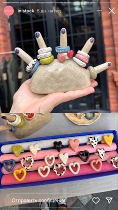 a hand holding some kind of rock with hearts on it and other items in the background