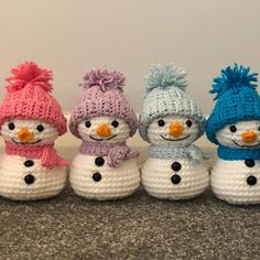 four crocheted snowmen with hats and scarves lined up in a row