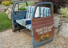 an old truck with a couch in the bed is sitting on some gravel and rocks