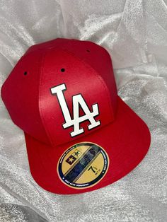 a los angeles dodgers baseball cap sitting on top of a white sheet