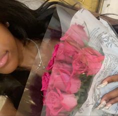 a woman laying on top of a bed next to pink roses