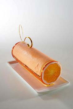 an orange slice on a white plate with a gold ring hanging from it's end