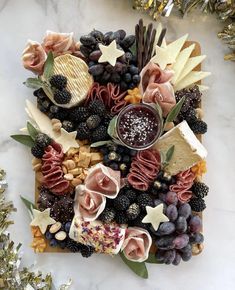 a platter filled with cheese, fruit and crackers on top of a marble counter