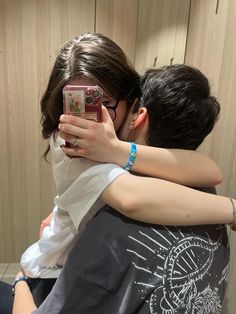 a man and woman hugging each other while taking a selfie with their cell phone