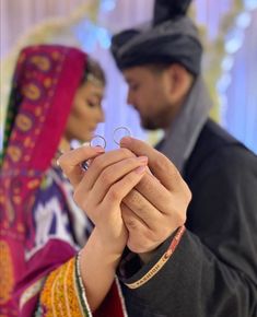 a man and woman standing next to each other holding their hands together in front of the camera