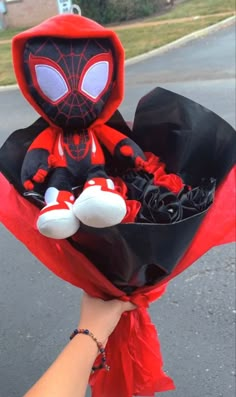 someone is holding a stuffed spider man in a red and black outfit with roses on it