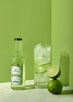 a bottle of lemonade next to a glass and lime