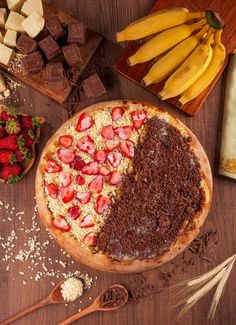 a chocolate cake with strawberries and other desserts around it on a wooden table