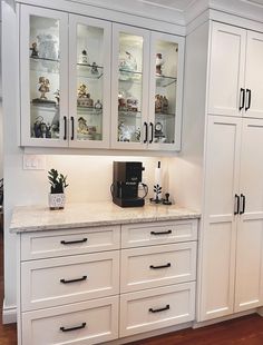 a kitchen with white cabinets and marble counter tops