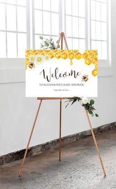 a welcome sign on an easer for a baby shower with flowers and greenery