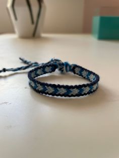 two blue and white braided bracelets sitting on top of a table next to a vase