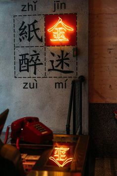 a red telephone sitting on top of a table next to a wall with chinese writing