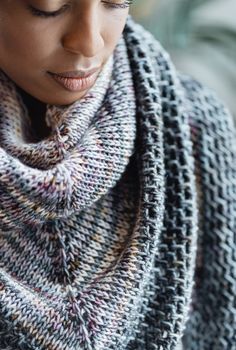 a close up of a woman wearing a knitted shawl with her eyes closed