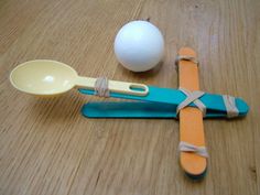 a wooden table topped with two spoons and an egg