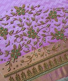 a purple and gold saree with green beads on it's border, sitting on a table