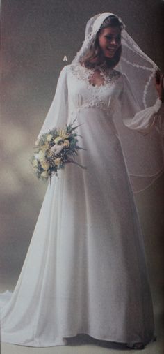 a woman in a white wedding gown and veil holding a bouquet with her hand on her hip