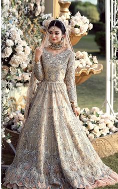 a woman in a wedding dress posing for the camera with flowers and roses behind her