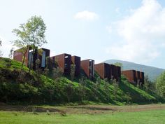 the building is made out of metal and sits on top of a grassy hill with trees