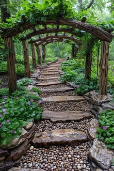 a stone path is surrounded by greenery and rocks in the woods, leading to a pergolated arbor