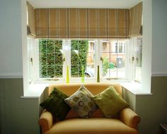 an orange chair with pillows in front of a window