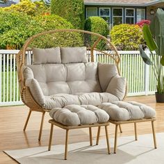 a wicker chair and footstool sitting on a deck with a potted plant