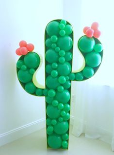 a large green cactus shaped sculpture sitting on top of a white floor next to a window