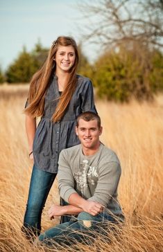 a man and woman sitting in tall grass