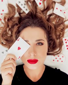 a woman laying down with playing cards in her hair