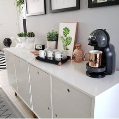 a coffee maker sitting on top of a white counter next to pictures and other items