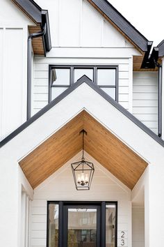 a white house with a black door and light fixture hanging from it's side