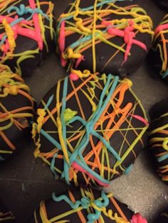 chocolate covered donuts with colorful icing and sprinkles on black surface