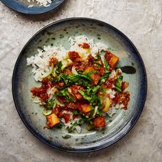 two plates filled with rice and vegetables on top of a white tablecloth next to each other