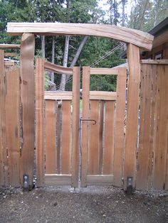 a wooden gate that is next to a house with trees in the backgroud