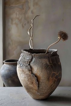 two vases sitting on top of a table with a plant in one of them