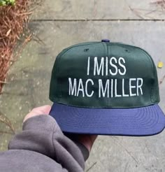 a person wearing a green and blue hat with the words i miss mac miller on it