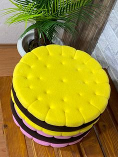 a stack of yellow and pink stools sitting on top of a wooden floor next to a potted plant