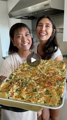 two women holding up a large casserole dish